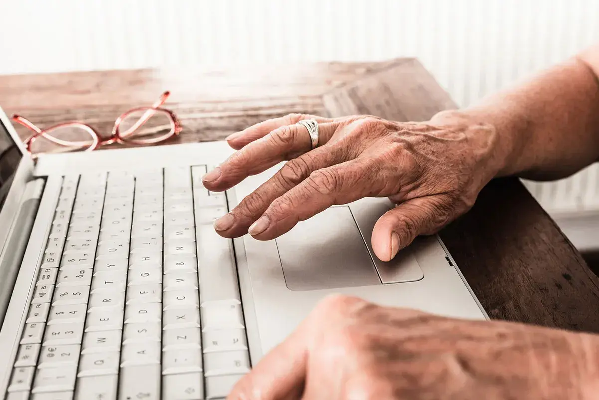 the hands of an older person using a laptop
