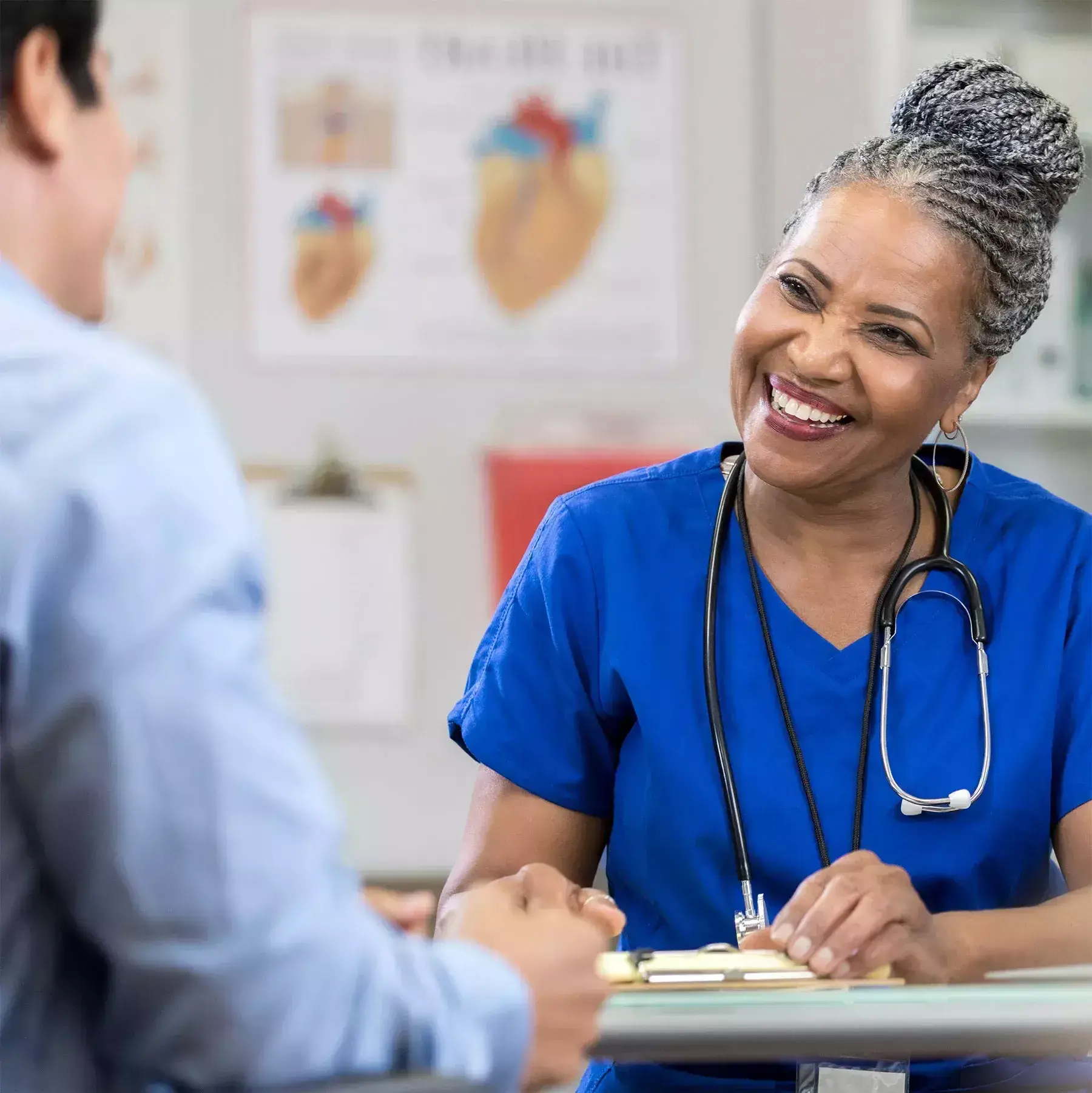 a smiling seated doctor talks to a patient